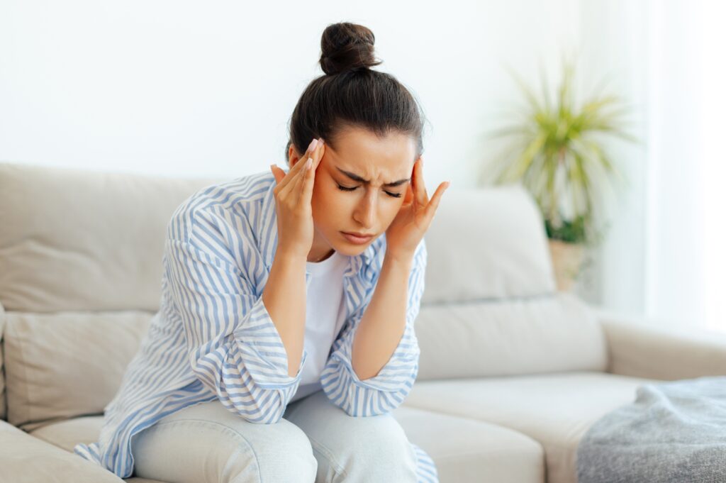 young woman touching her temples in pain from a headache