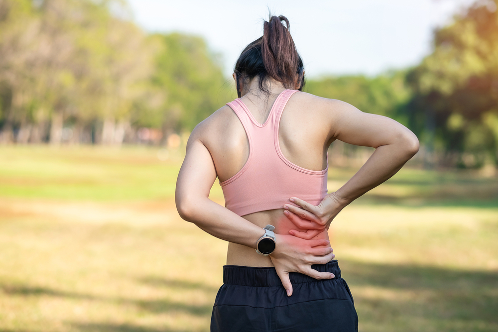 A woman holding her lower back while jogging